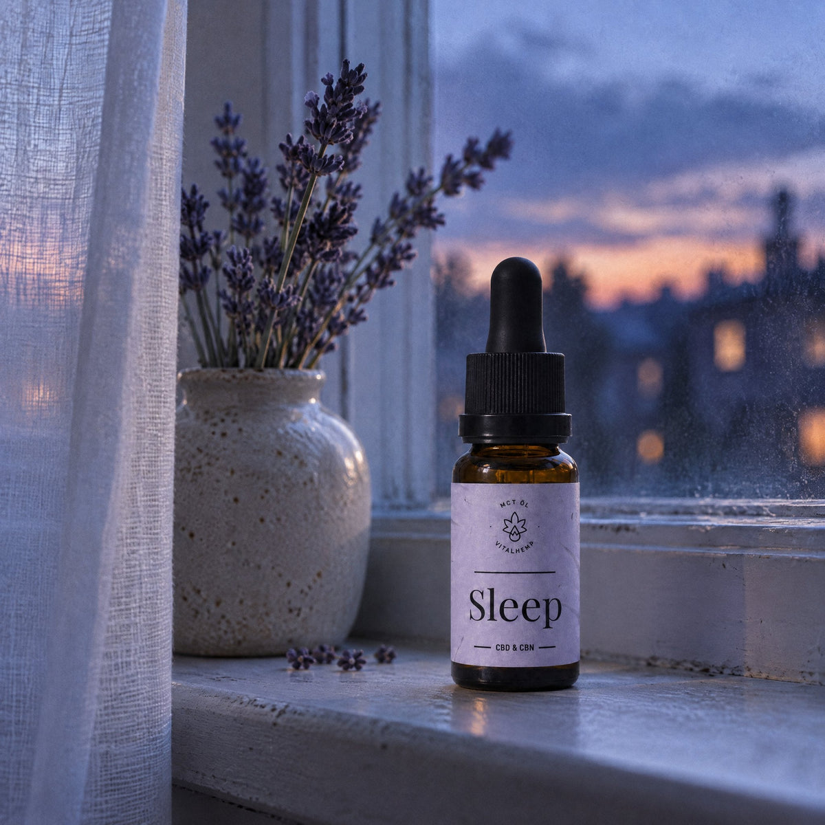 VITALHemp Sleep Flasche auf der Fensterbank in der Abenddaemmerung neben einer Vase mit Lavendel
