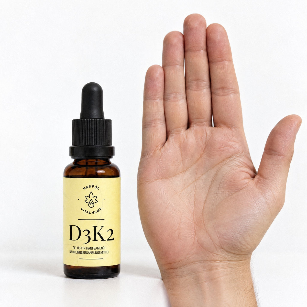 VITALHemp Vitamin D3+K2 Flasche neben einer Hand zum Groessenvergleich
