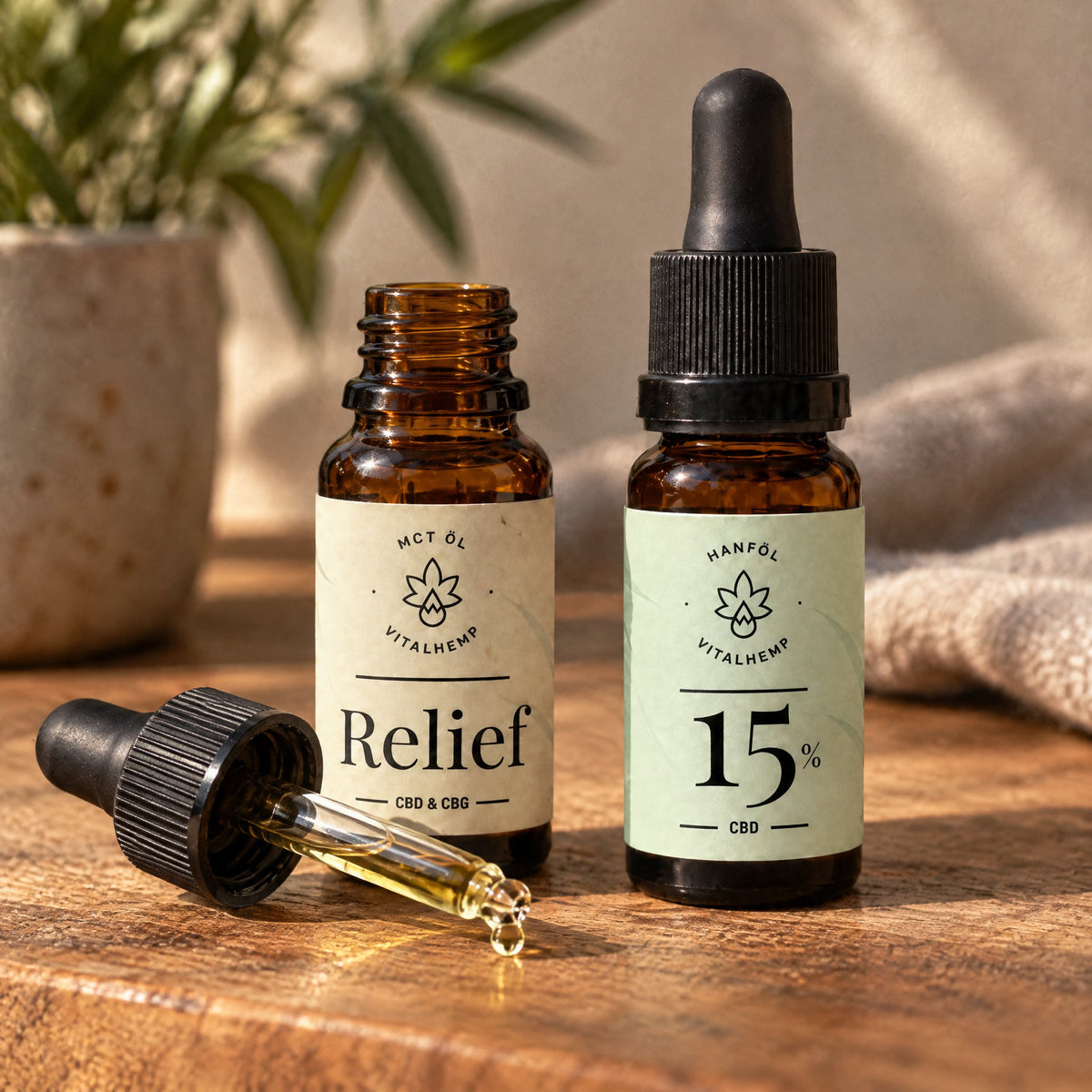 Offene VITALHemp Relief Flasche mit ihrer Pipette davor, geschlossene CBD-Oel 15 Prozent Flasche daneben