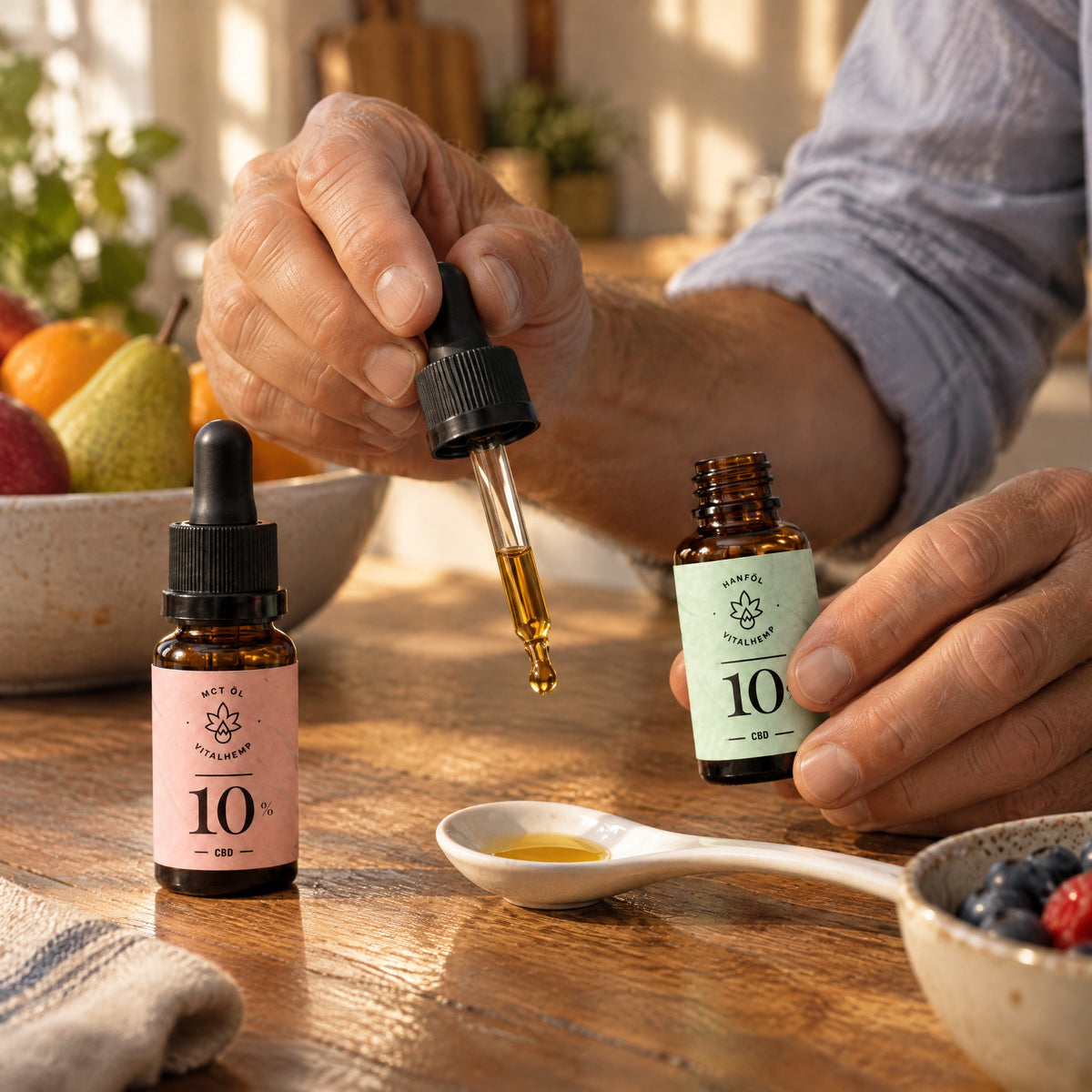 Hände geben einen Tropfen CBD-Öl 10 % in Bio-Hanföl auf einen Keramiklöffel, daneben die MCT-Öl-Flasche