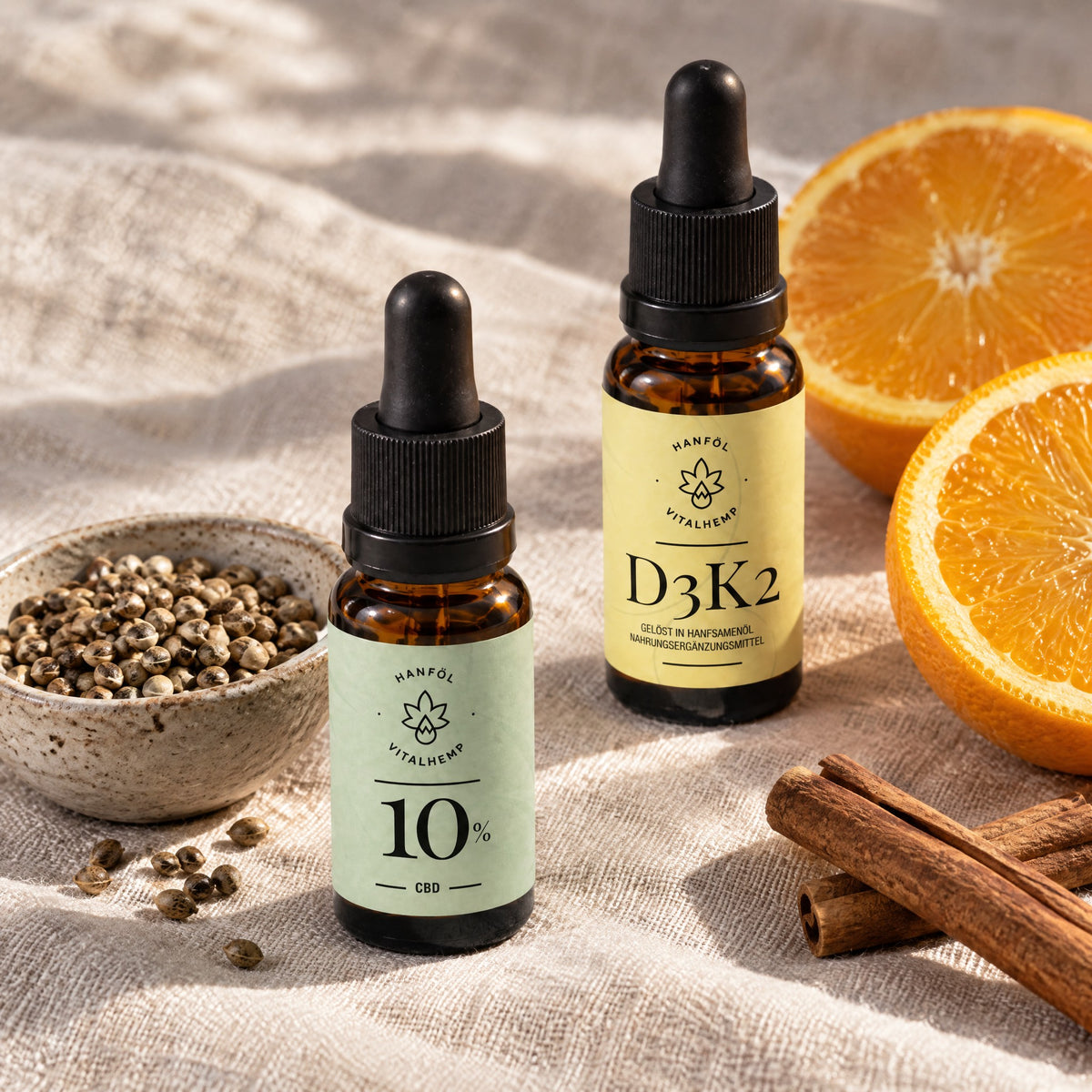 CBD-Öl 10 % neben Hanfsamen und Vitamin D3+K2 neben Orangenhälften und Zimtstangen